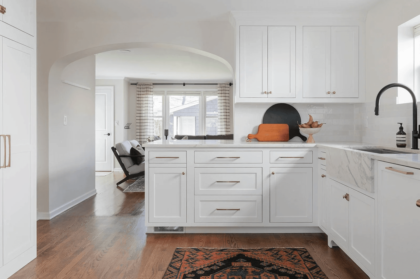 The same kitchen as built — white shaker cabinetry, marble countertops, gold hardware